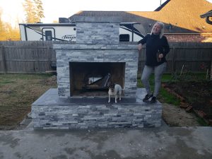 Completed DIY outdoor fireplace with owner and dog