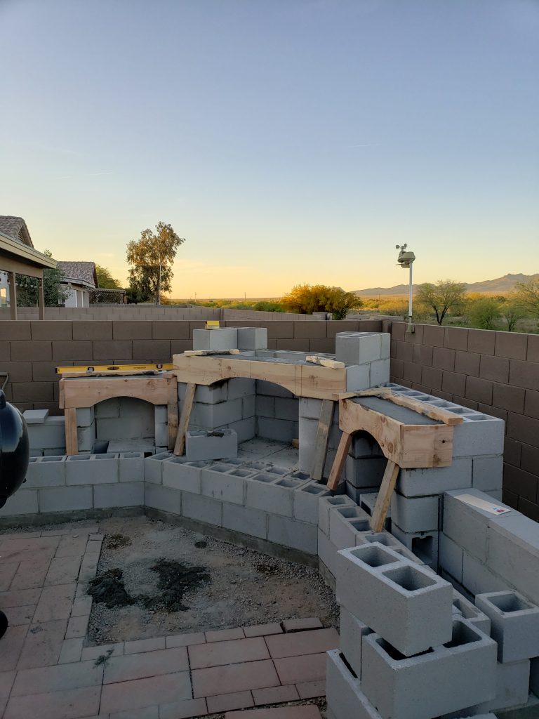 Masonry construction outdoor fireplace with storage and concrete lintels