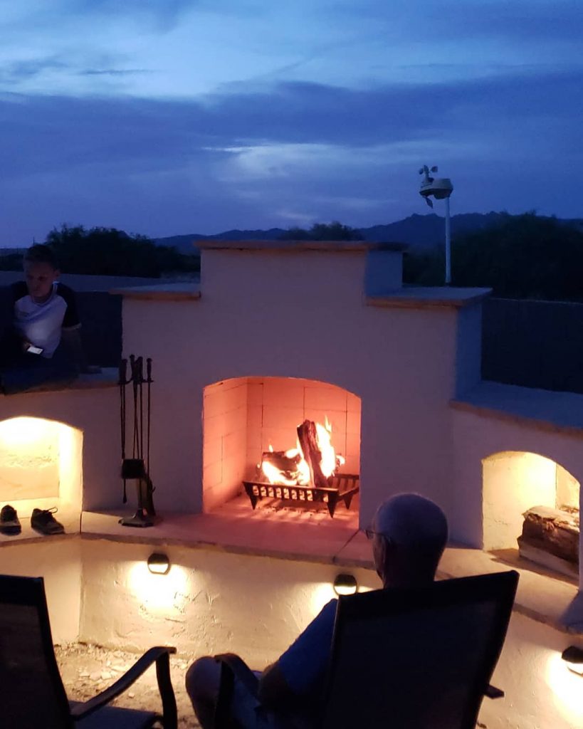 DIY outdoor backyard fireplace at night with fire