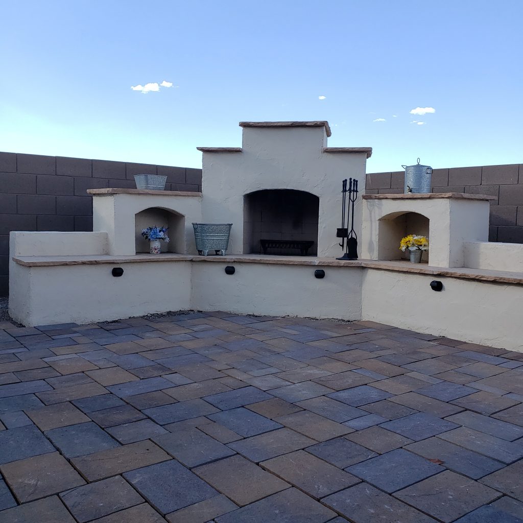 Finished DIY outdoor fireplace with painted stucco and brick patio