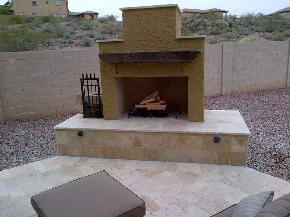 backyard outdoor DIY fireplace built on patio with travertine and stucco finish.